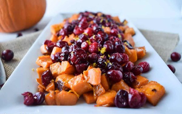 Roasted sweet potatoes with cranberries on a white tray.
