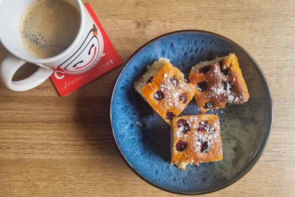 A blue plate with three pieces of cake and a cup of coffee.