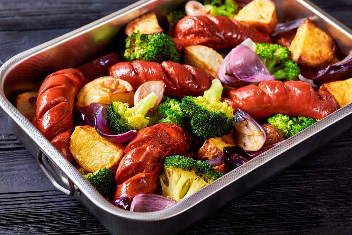 A metal pan filled with vegetables and sausages.