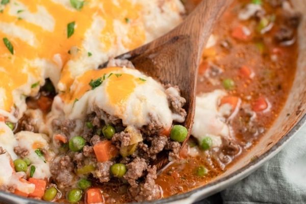 Shepherd's pie in a pan with wooden spoon.