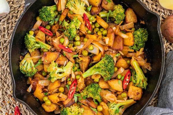 Potatoes cooked on a skillet with vegetables. 