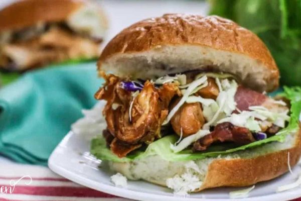 Slow cooker BBQ chicken on a bun on a white plate.