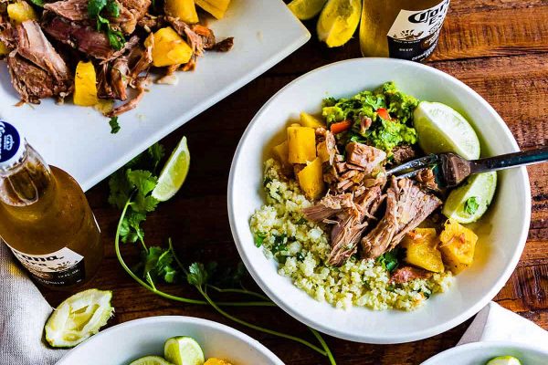 Slow cooker pork with rice on a brown table.