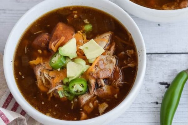 Mexican chicken soup in a bowl on a wooden table.