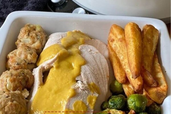 Turkey crown in a casserole dish with biscuits and sides. 