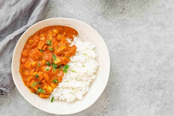 White bowl with rice and slow cooker vegan tikka masala. 