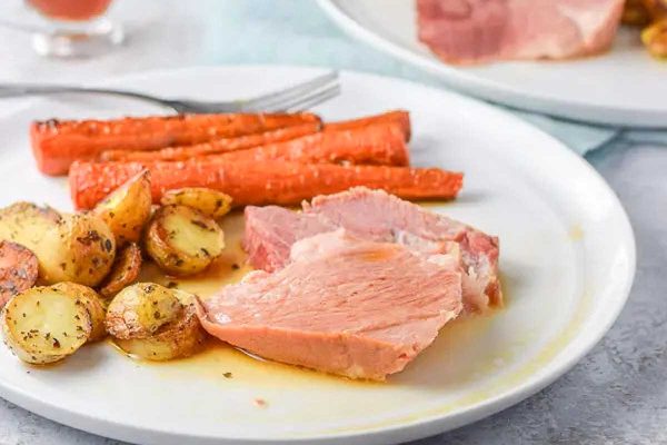 Pork shoulder with carrots on a white plate.