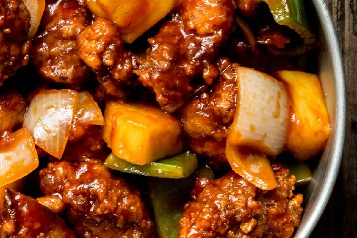 A bowl of sweet and sour pork smothered in sauce.