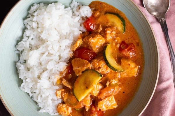 A bowl of curry with rice and vegetables.