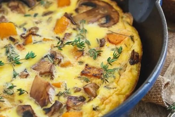 Breakfast frittata in a cast iron skillet with mushrooms and vegetables. 