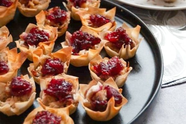 Turkey and cranberry filo tarts served on a black round plate. 