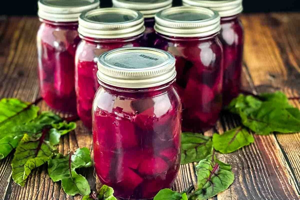 Beet pickles in mason jars on a wooden table.
