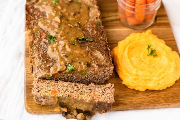 Sliced turkey meatloaf on a wooden chopping board. 