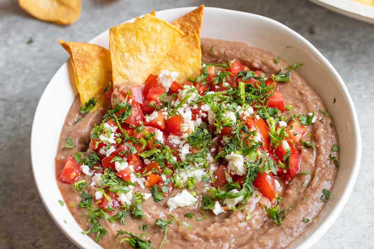 Bean dip with diced tomatoes and cheese crumbled on top.