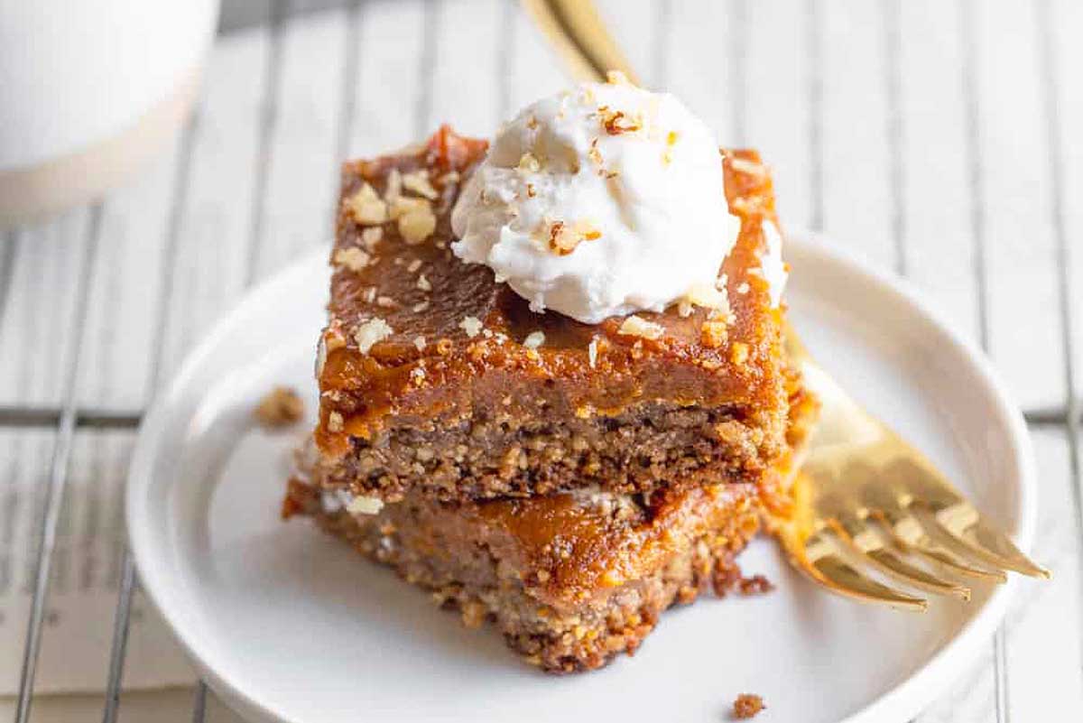 Pumpkin pie bars stacked up on a white plate with a fork.