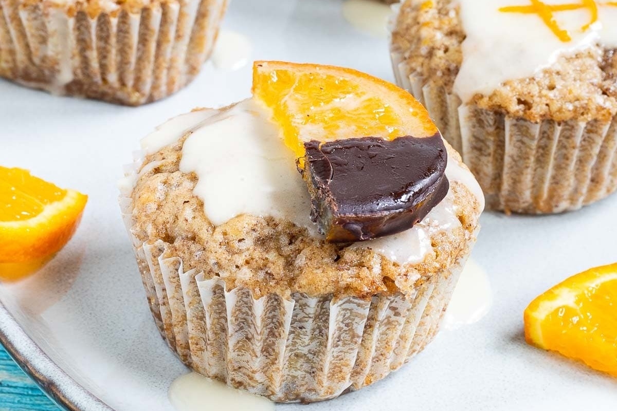 Orange muffins with a chocolate covered orange slice on top.