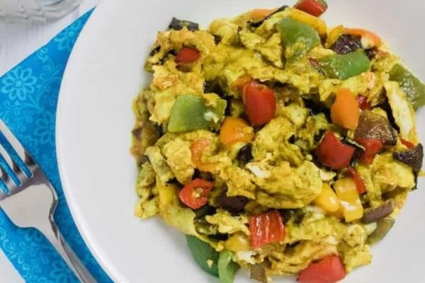 Scrambled eggs with vegetables on a white plate.