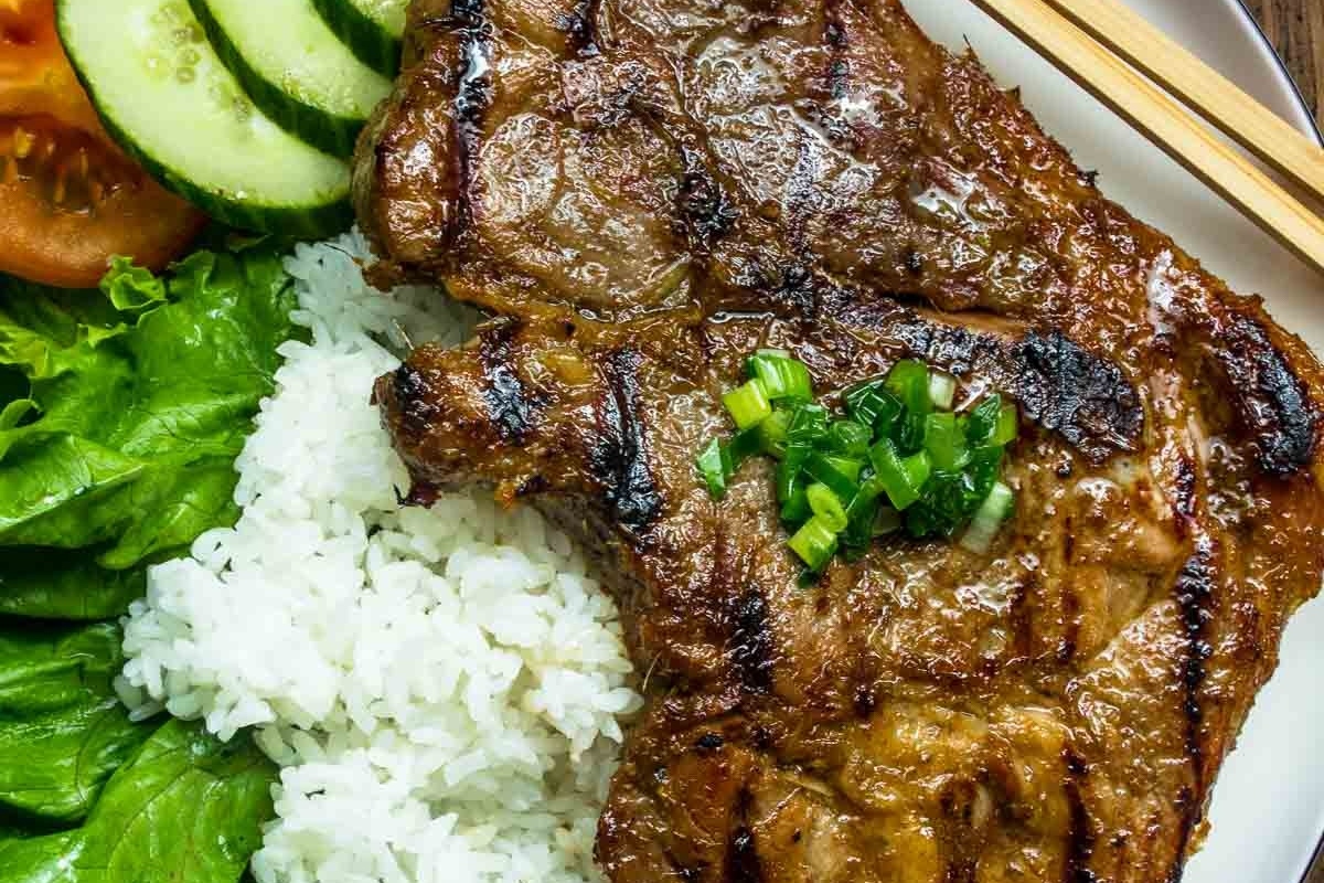 Pork chops on a plate served with rice and vegetables.