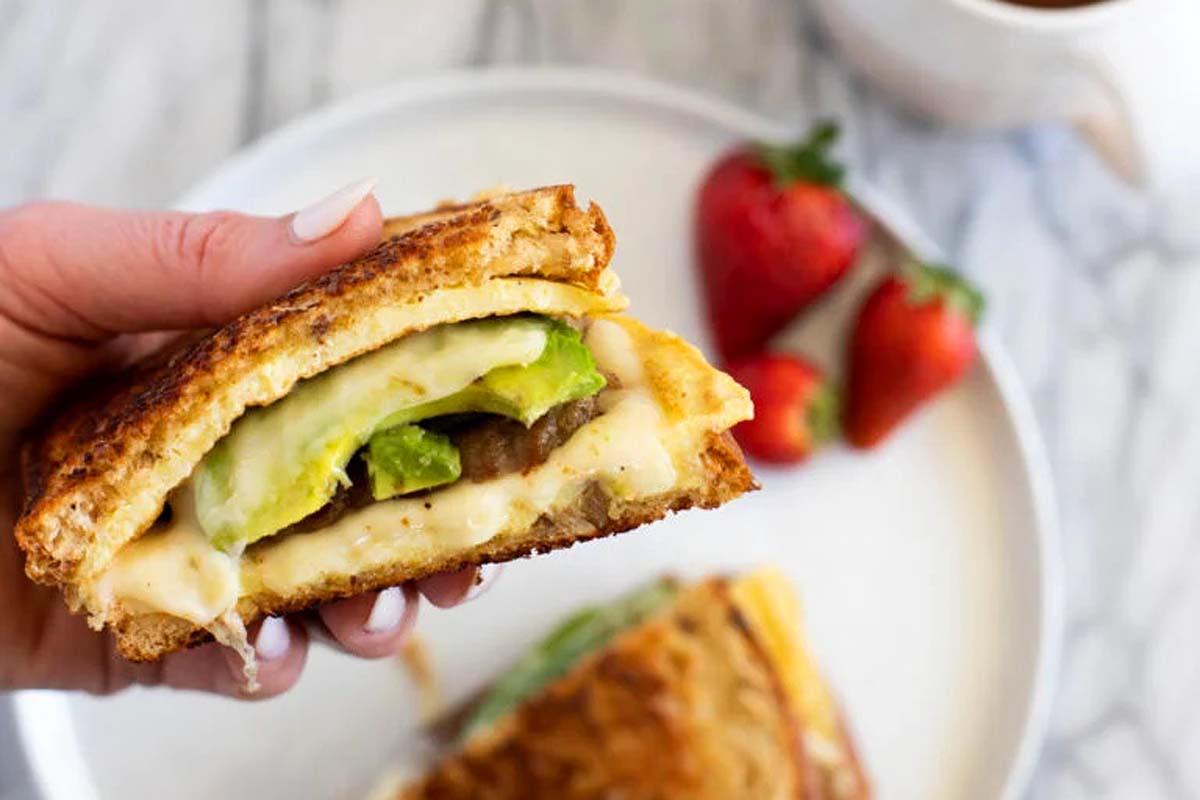 A hand holding an egg sandwich.