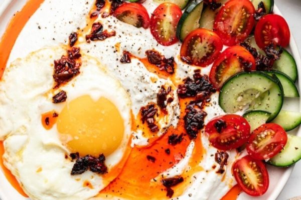 A plate with a fried egg, tomatoes and cucumbers.