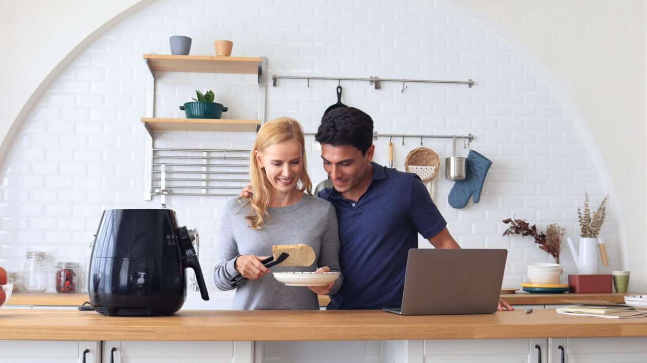 A couple cooking in the kitchen with an air fryer.