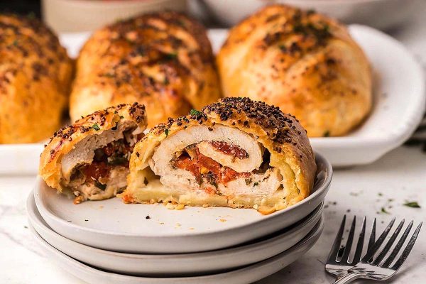 A chicken breast stuffed with bruschetta cut in half on a plate.