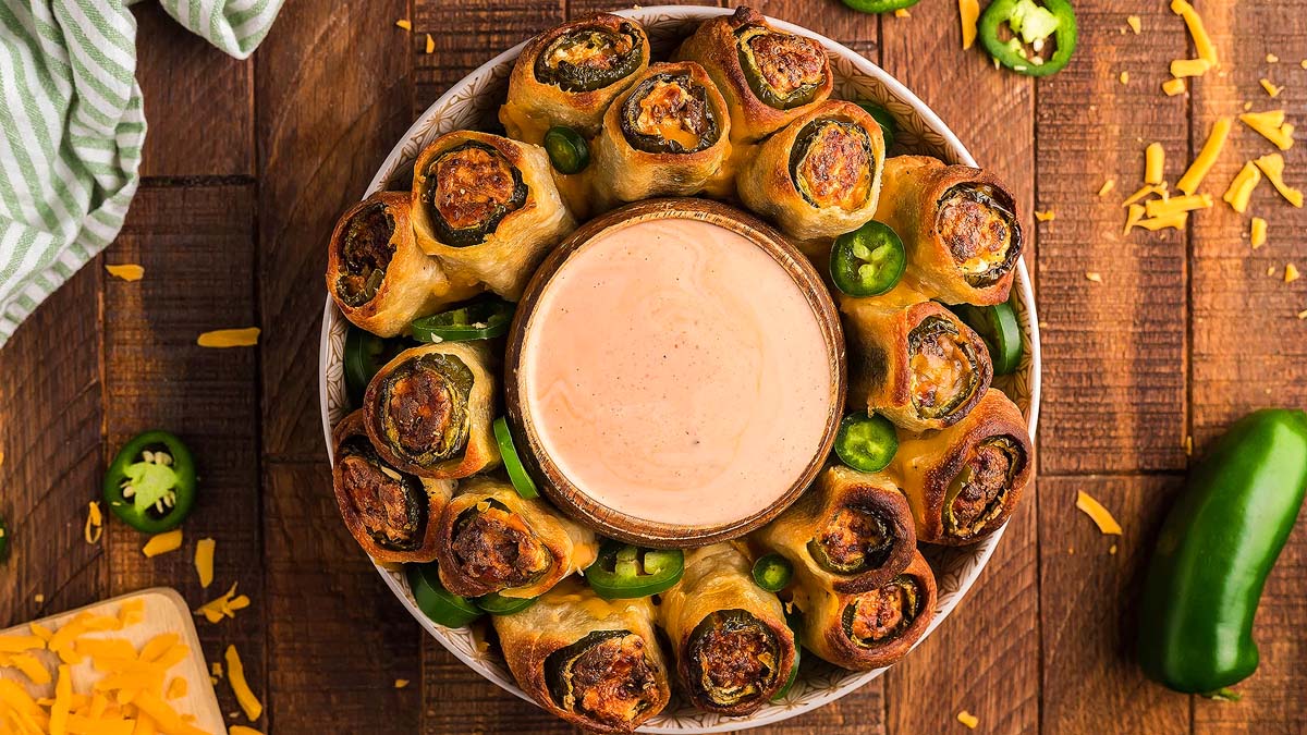 Air fried jalapeno popper rolls on a plate with a bowl of dip. This is one of the best game day recipes.