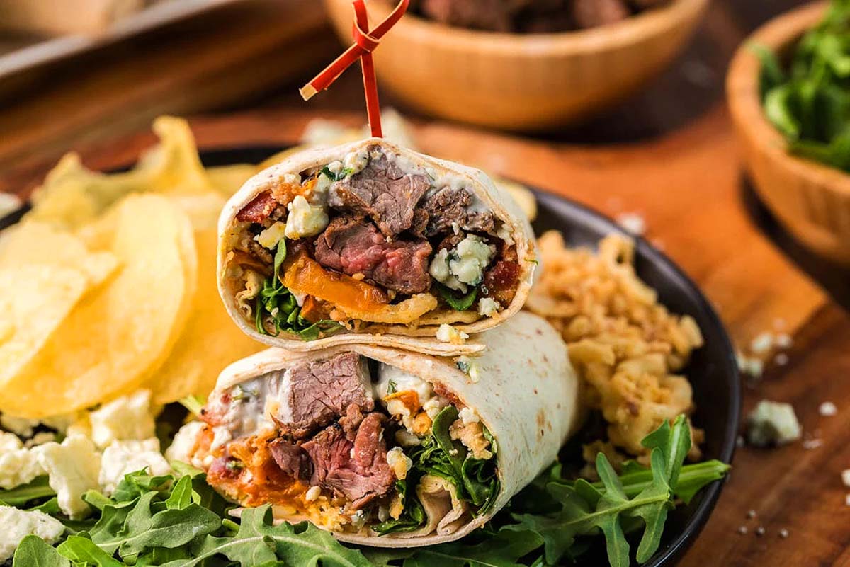 A steak wrap cut in half on a plate.