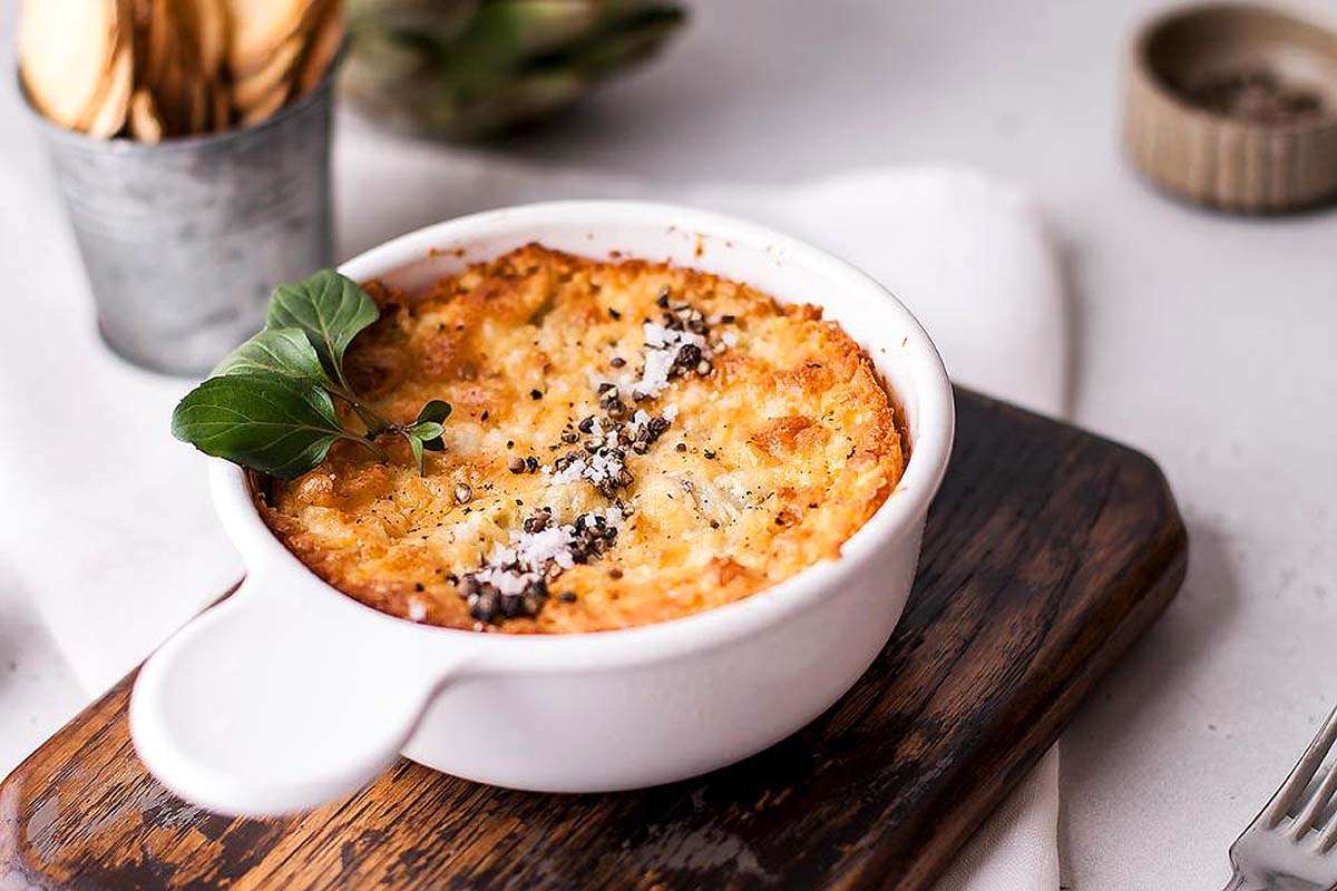 An oven dish with a baked artichoke dip.