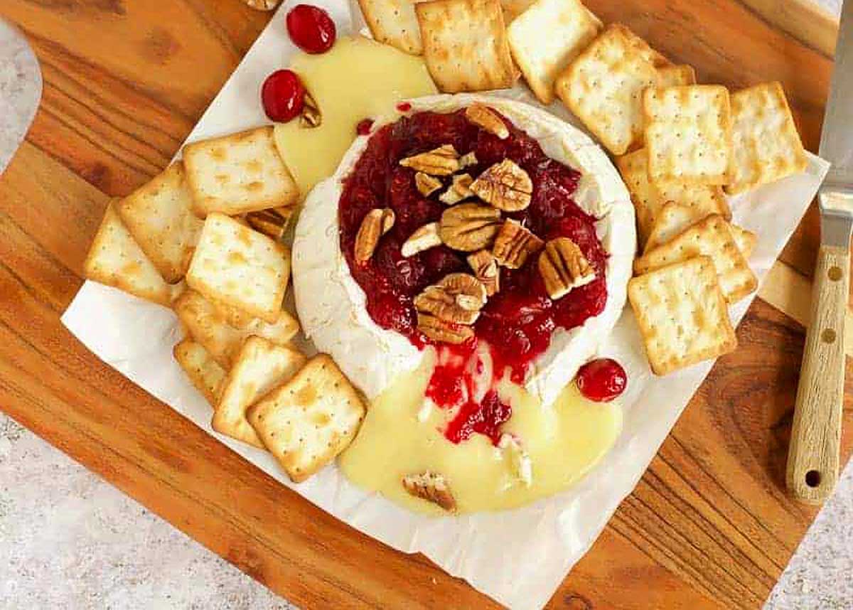Melted brie cheese with cranberry sauce and pecans on top.