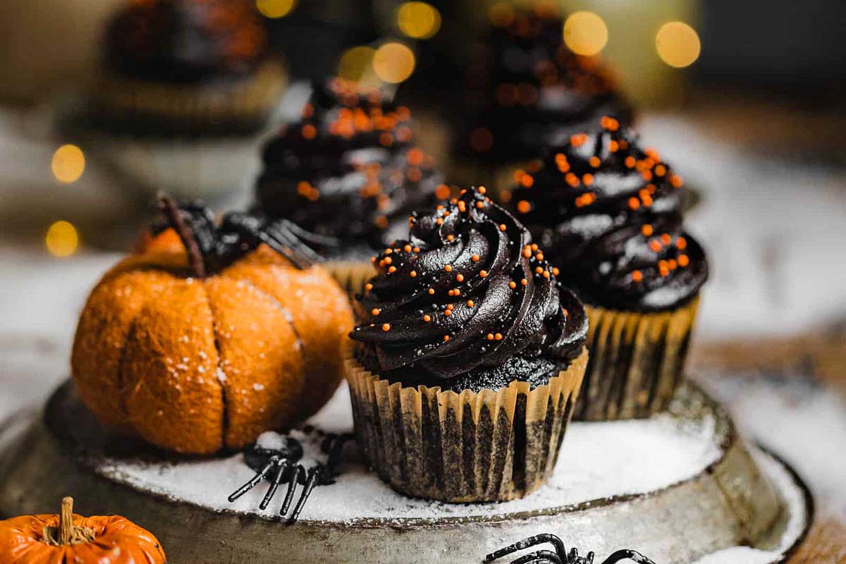 Black Velvet Cupcakes with range sprinkles and pumpkins on the side.