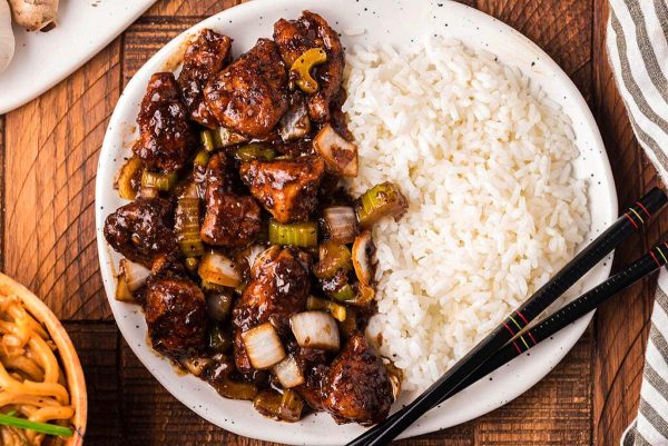 Black pepper chicken and rice on a plate.