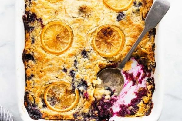 Lemon cake in a casserole dish with lemons on top.