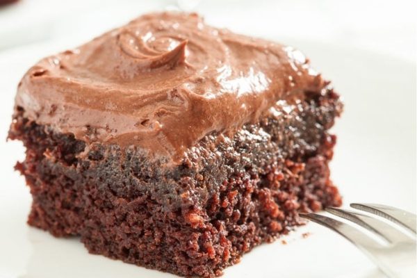 Chocolate dump cake with frosting on a white plate.