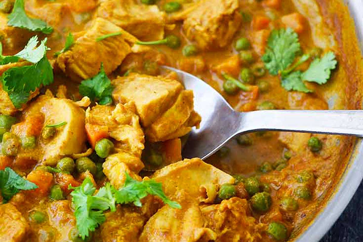 Coconut Curry Chicken being scooped from a bowl. Delicious chicken recipes! 