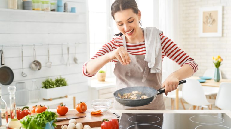 Healthy food at home. Happy woman is preparing the proper meal in the kitchen.
