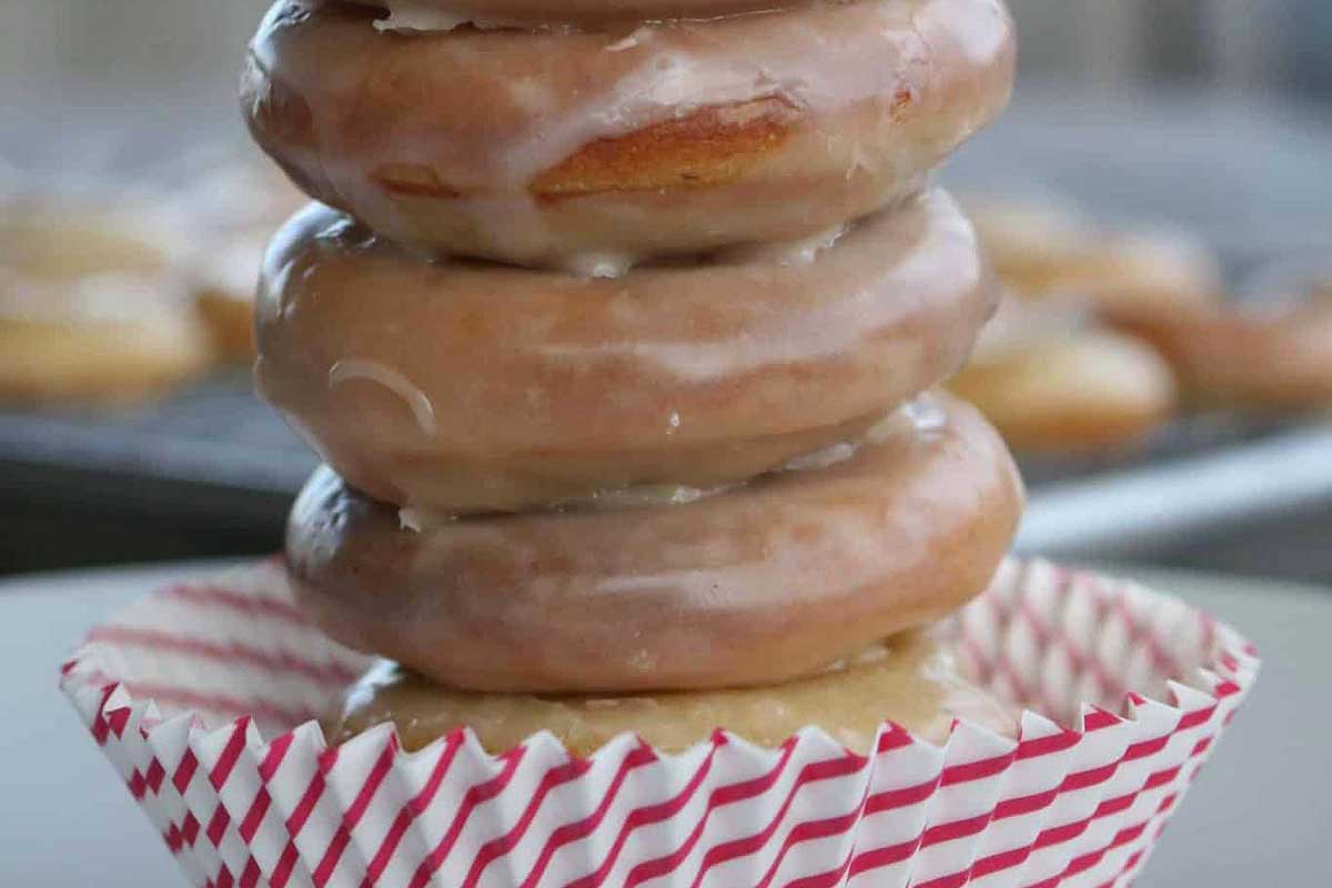 Donuts krispy Kreme on a plate with a stack of other donuts.
