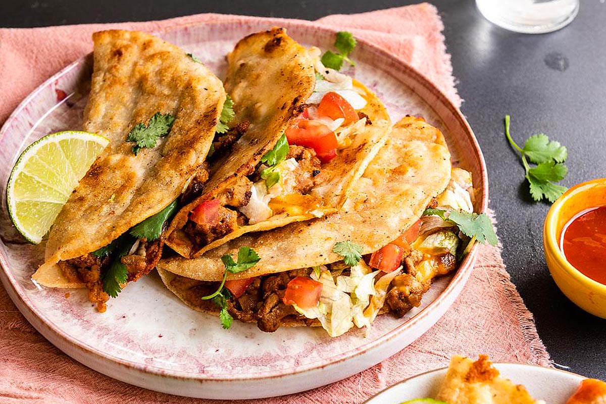 Mexican tacos on a plate with a lime wedge.