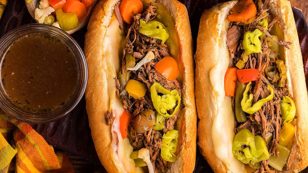 Two Italian beef buns with peppers on top.