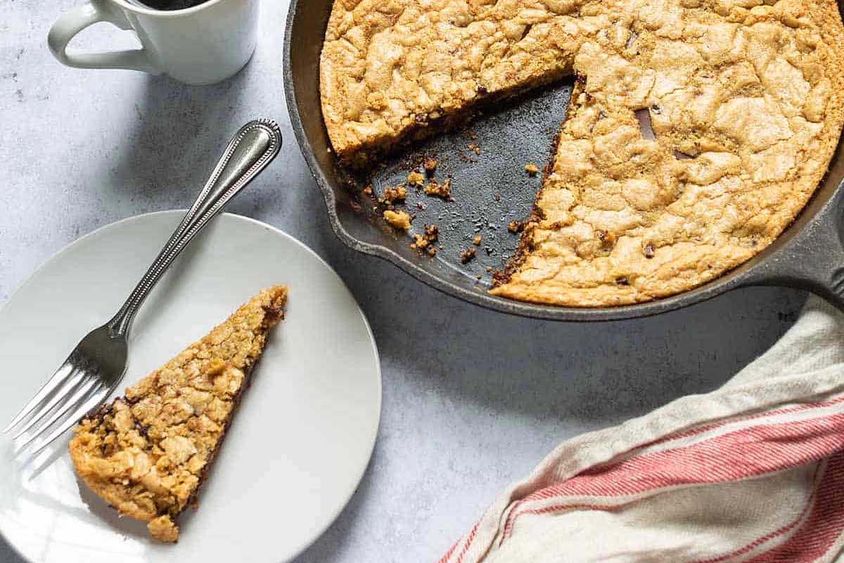 Skillet cookie in a cast iron pan with one slice out.