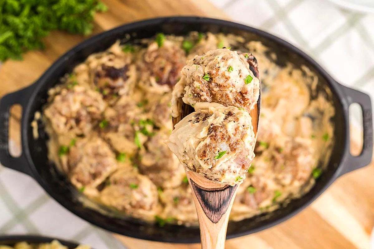 Ikeas meatballs being scooped from a casserole dish.