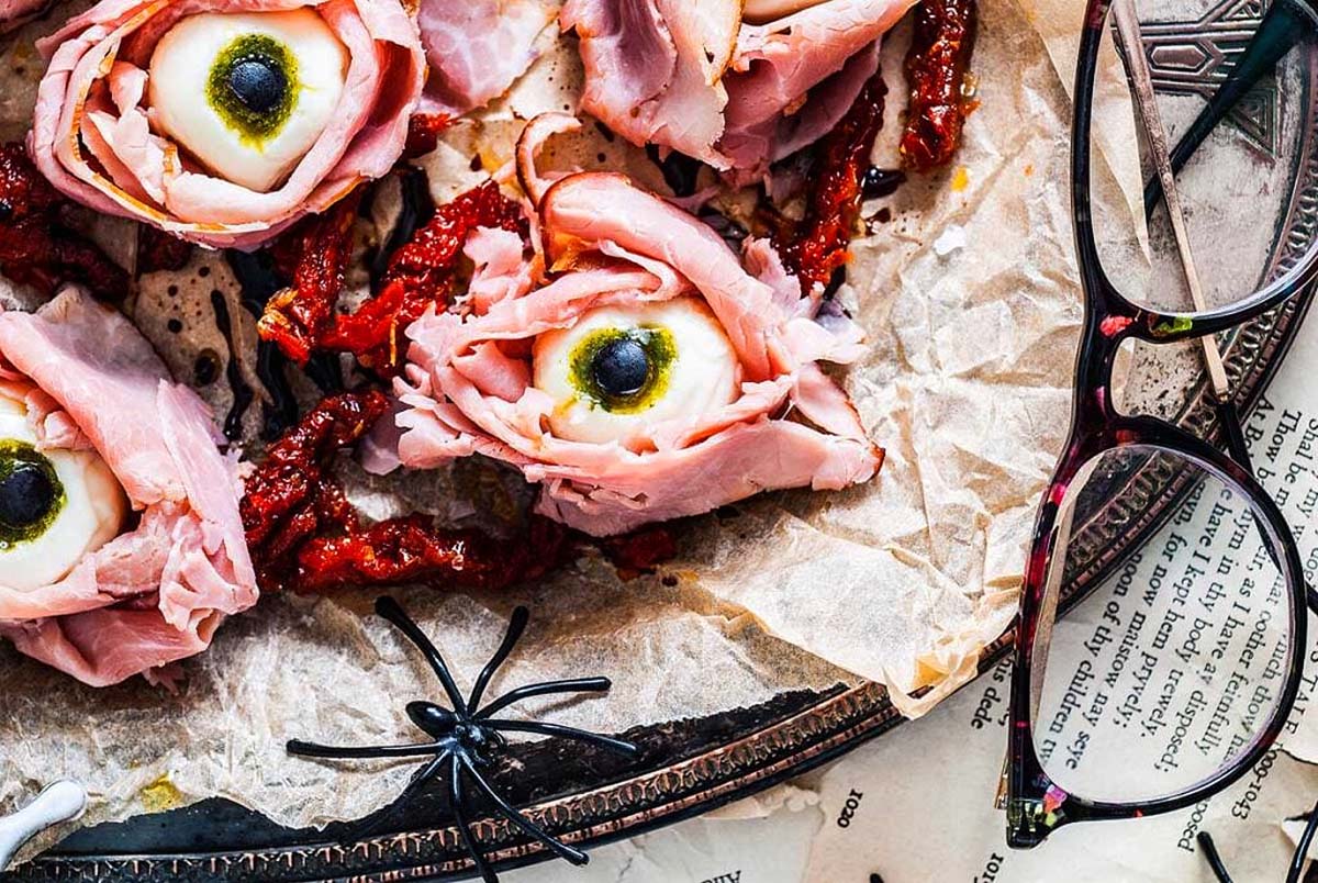 A Halloween appetizer that is eyeballs made with cheese balls, ham and olives. 