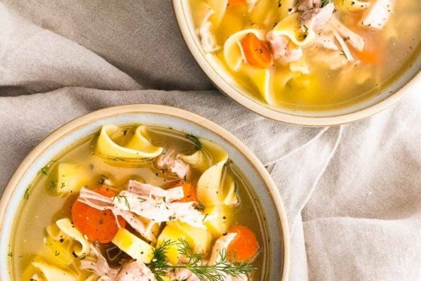 Chicken noodle soup in two bowls with carrots.