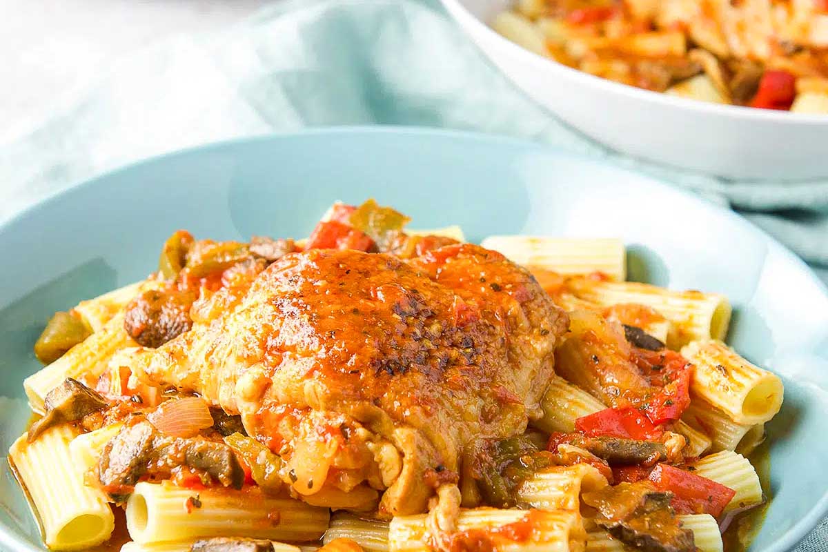 A bowl of pasta with chicken and vegetables in it.