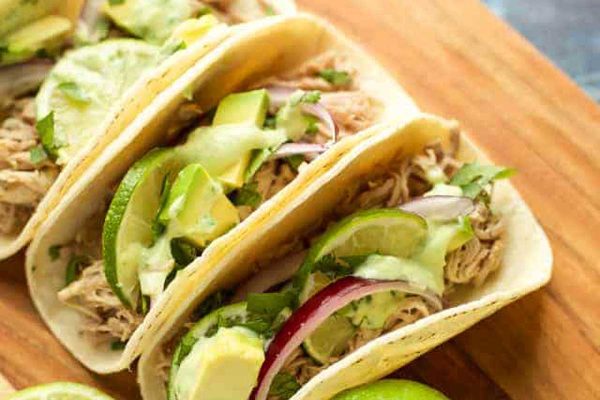 Instant pot pork tacos on a cutting board with limes.