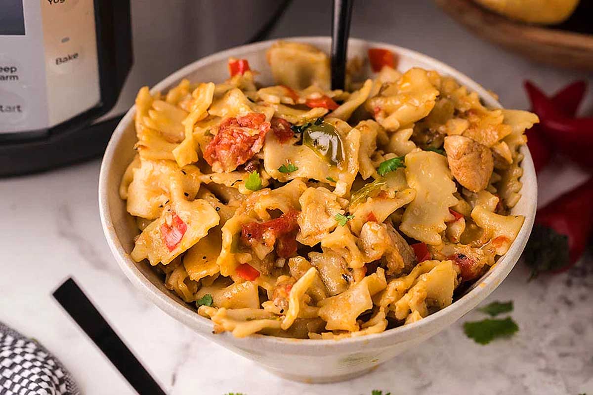 A bowl of pasta in front of an instant pot.