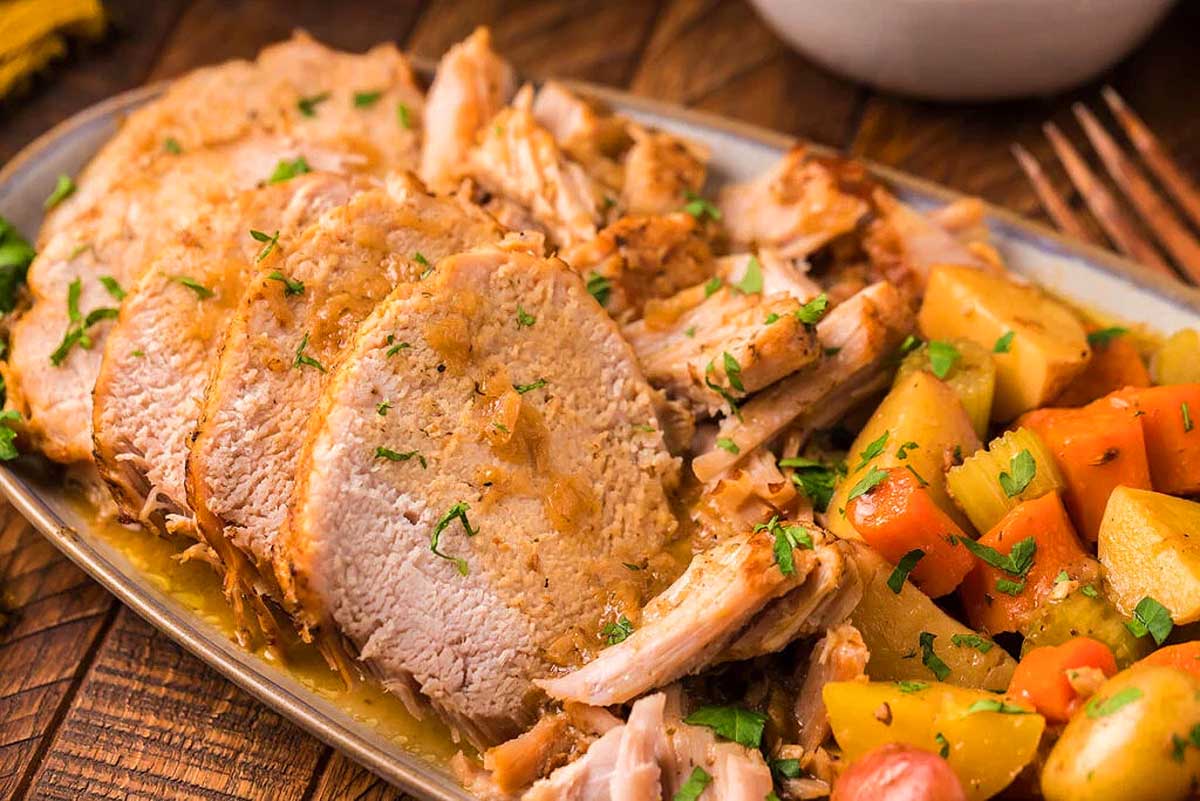 Pork tenderloin on a plate with potatoes and carrots. This is one of the best Instant Pot recipes.