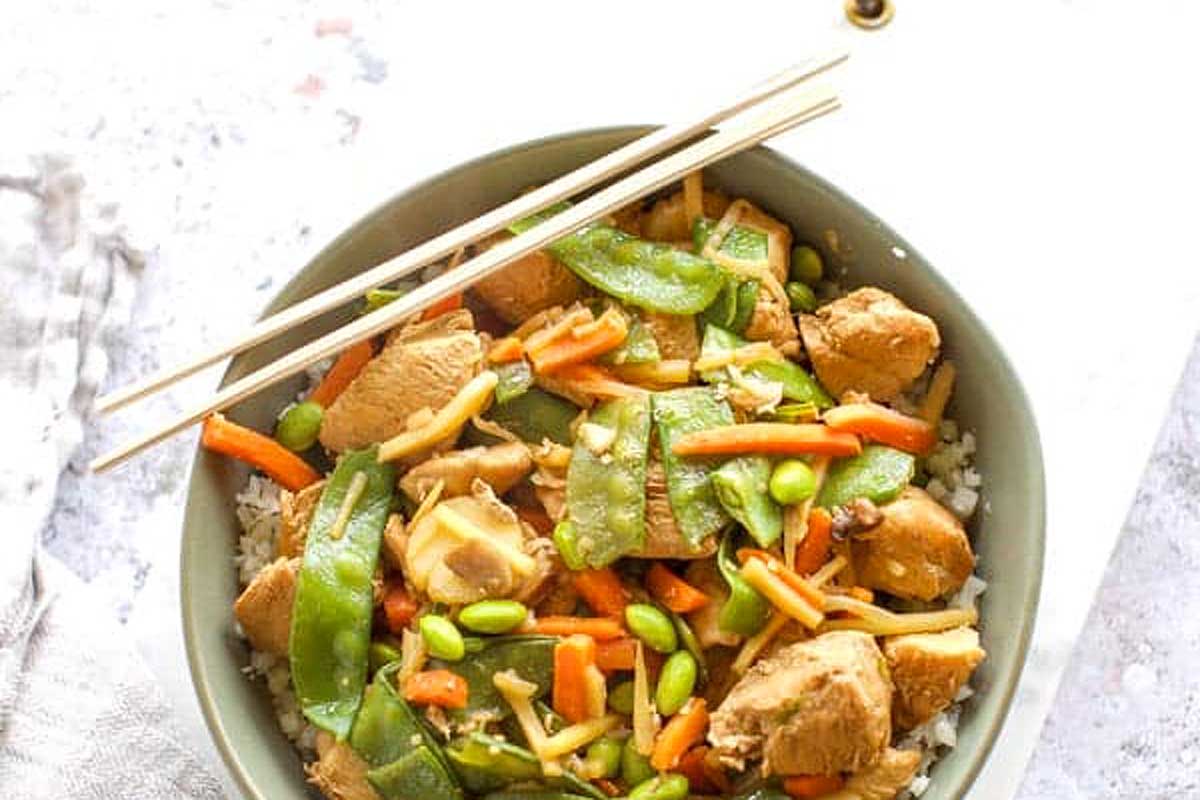 Chicken stir fry in a bowl with chopsticks.