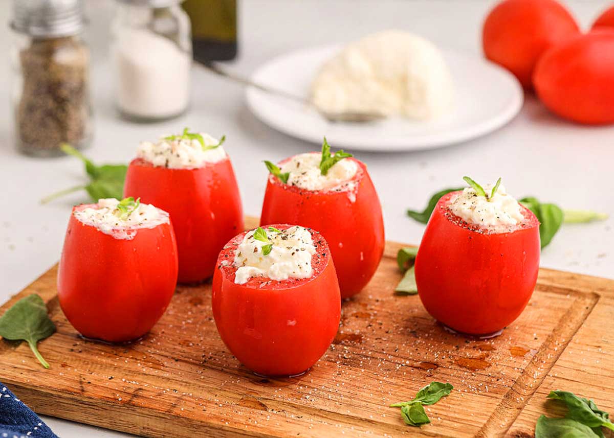 Tomato stuffed with burrata on a cutting baord