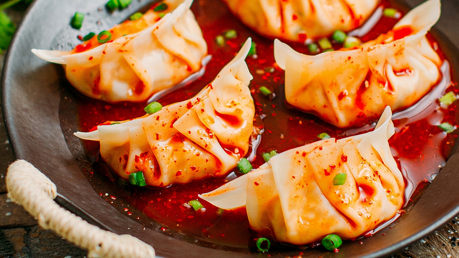 Plate of kimchi dumplings in sauce.